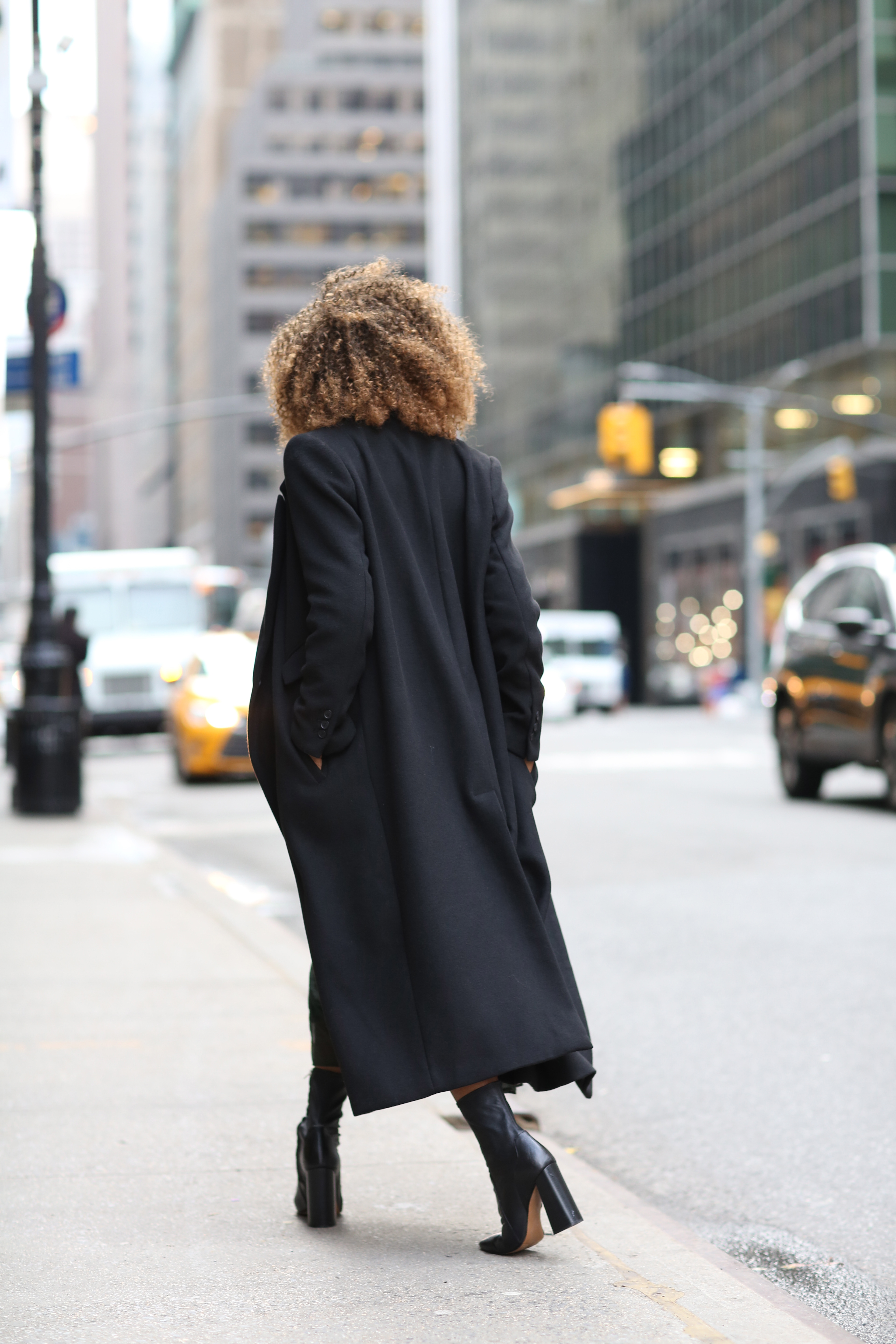 Karen Blanchard wearing a long black H&M coat with block heel ankle boots