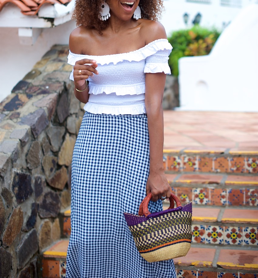 Karen Blanchard is carrying a off the shoulder white top with a gingham midi skirt and mini basket bag