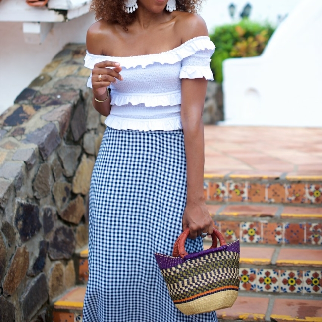 Karen Blanchard is carrying a off the shoulder white top with a gingham midi skirt and mini basket bag